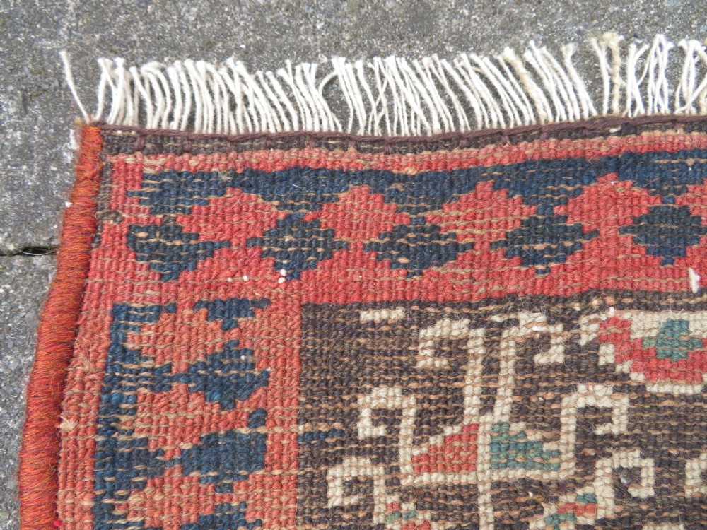 An antique hand-knotted Kurdish runner rug featuring five large geometric medallions in blue, red, and cream on a dark brown field. View XXI