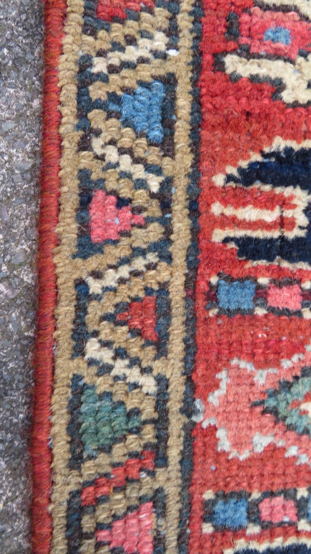 A long, narrow hand-knotted Persian Karaja wool rug runner featuring repeating geometric medallions in navy, blue, and cream against a rust red field. View X