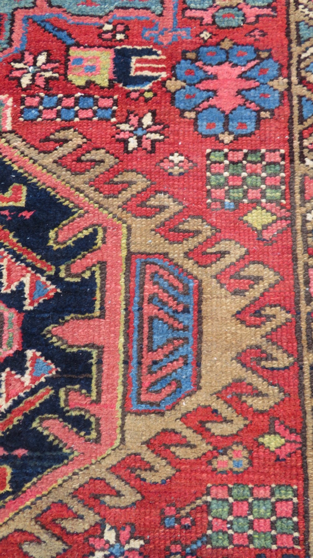 A long, narrow hand-knotted Persian Karaja wool rug runner featuring repeating geometric medallions in navy, blue, and cream against a rust red field. View XII