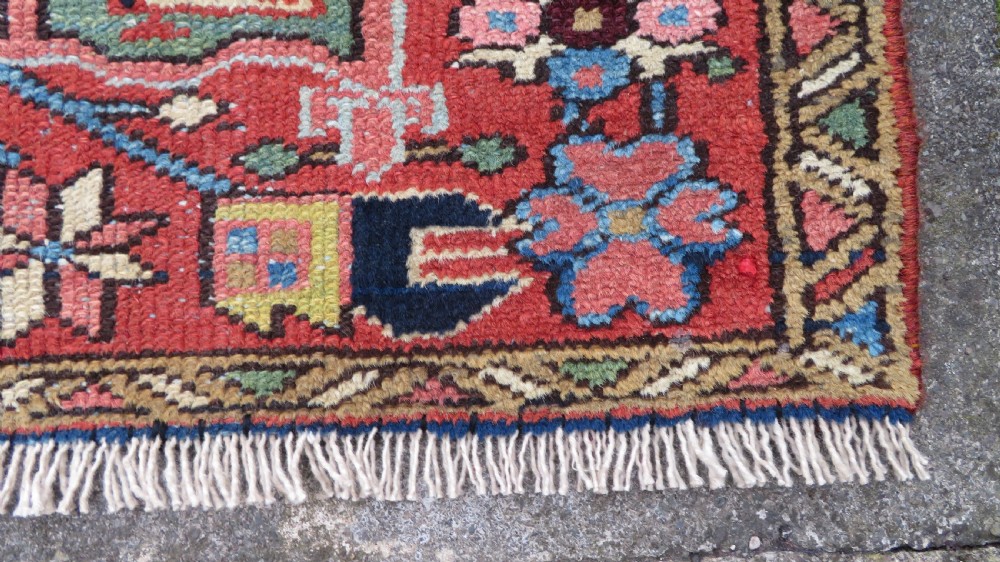 A long, narrow hand-knotted Persian Karaja wool rug runner featuring repeating geometric medallions in navy, blue, and cream against a rust red field. View XIV