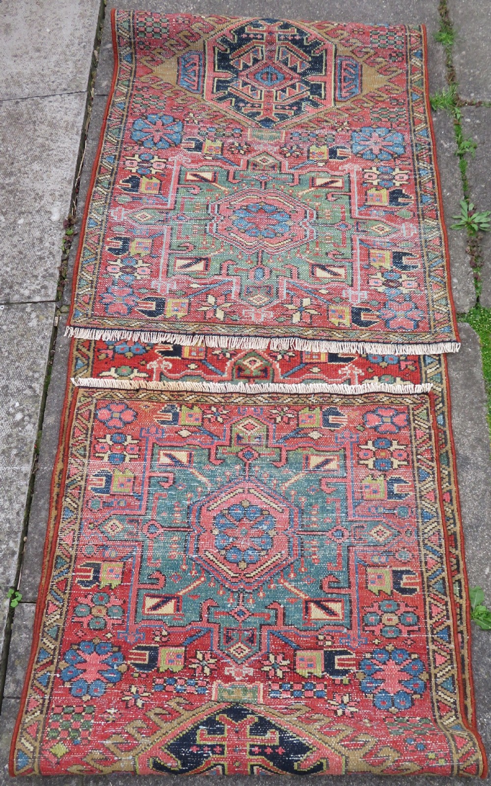 A long, narrow hand-knotted Persian Karaja wool rug runner featuring repeating geometric medallions in navy, blue, and cream against a rust red field. View XVIII