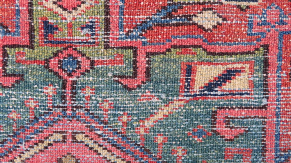 A long, narrow hand-knotted Persian Karaja wool rug runner featuring repeating geometric medallions in navy, blue, and cream against a rust red field. View XX