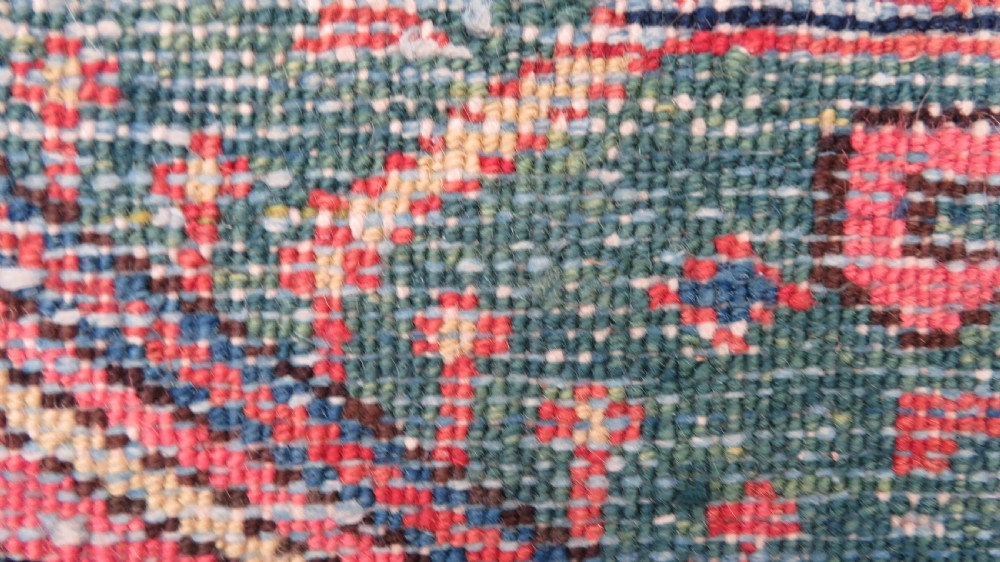 A long, narrow hand-knotted Persian Karaja wool rug runner featuring repeating geometric medallions in navy, blue, and cream against a rust red field. View XXI