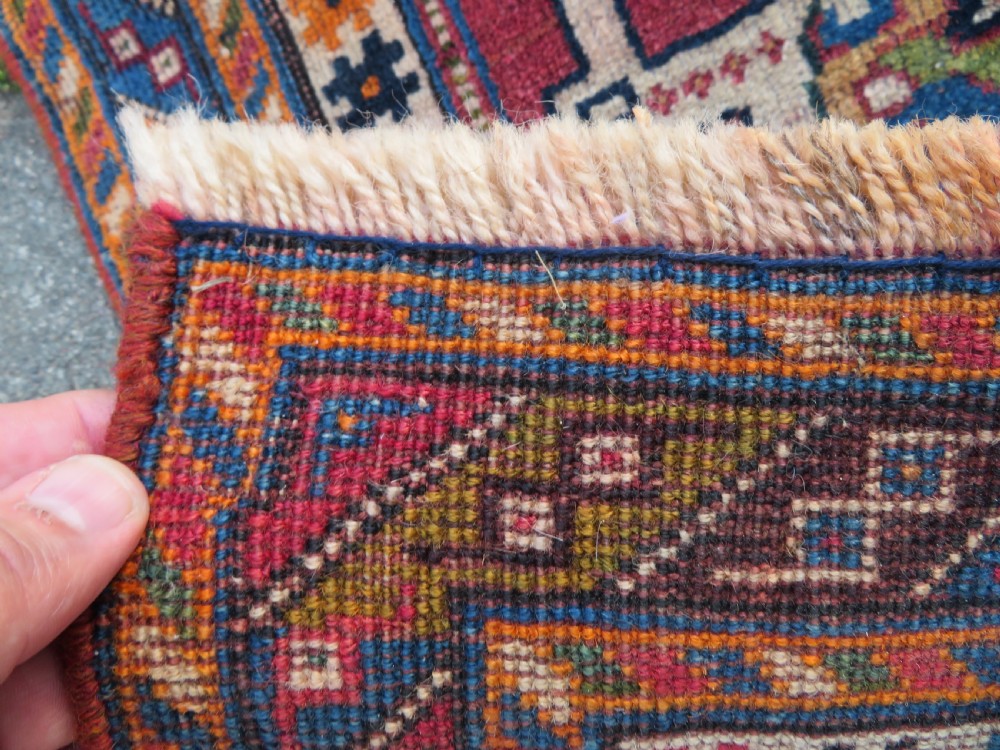An antique Qashqai hand-knotted wool rug featuring a central diamond medallion surrounded by geometric tribal motifs in shades of navy blue, terracotta red, and cream. View XV