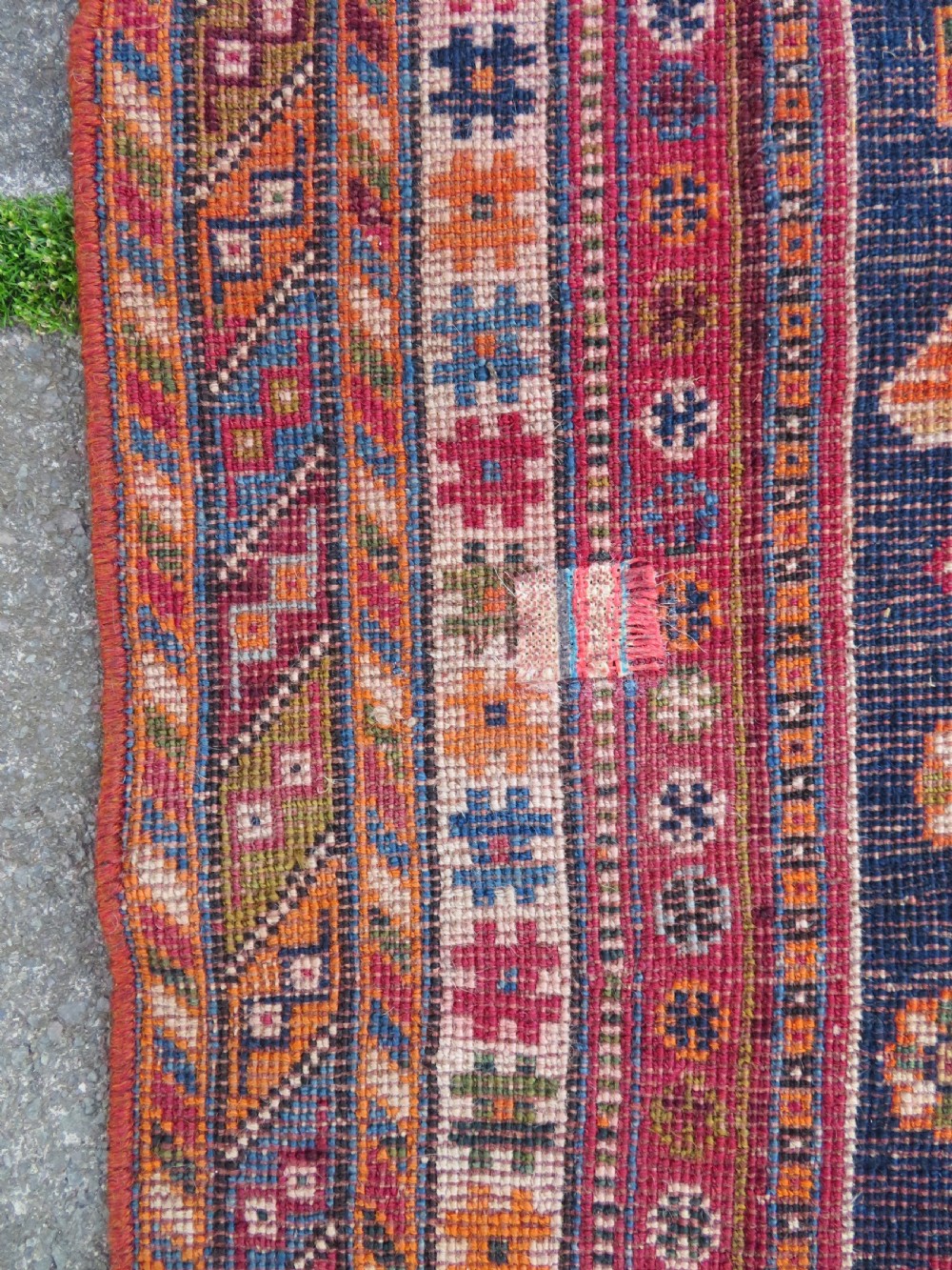 An antique Qashqai hand-knotted wool rug featuring a central diamond medallion surrounded by geometric tribal motifs in shades of navy blue, terracotta red, and cream. View XXIV