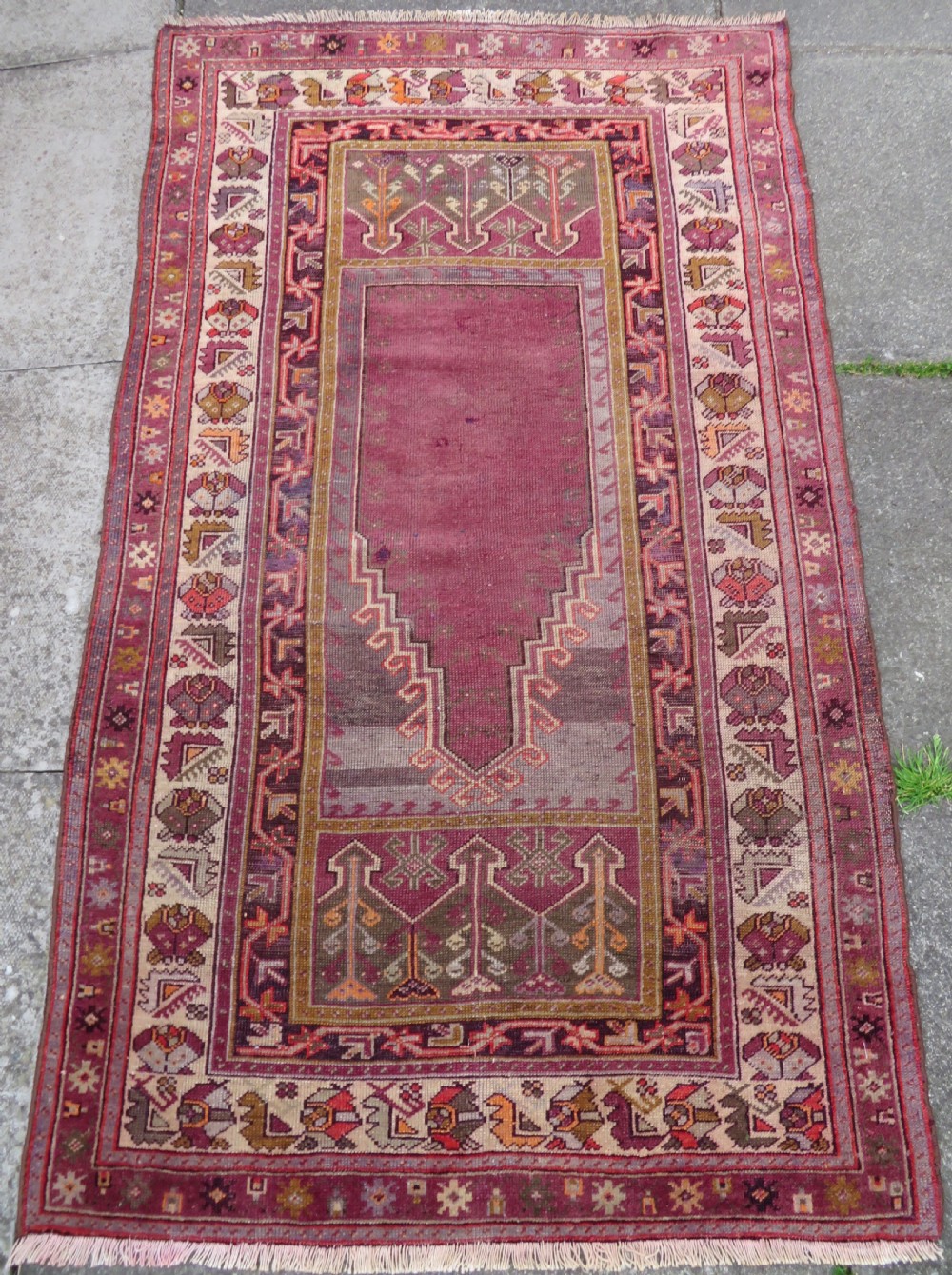 A late 19th-century hand-knotted Anatolian prayer rug featuring a deep magenta mihrab motif framed by geometric patterned borders in cream, ochre, and purple tones. View II