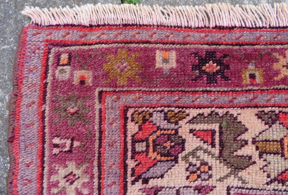 A late 19th-century hand-knotted Anatolian prayer rug featuring a deep magenta mihrab motif framed by geometric patterned borders in cream, ochre, and purple tones. View VI