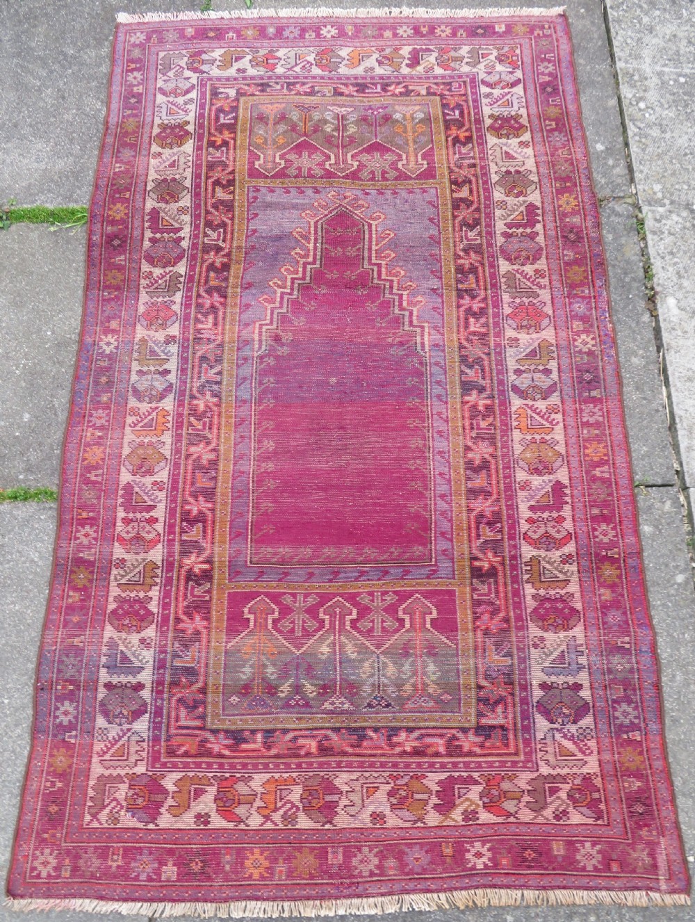 A late 19th-century hand-knotted Anatolian prayer rug featuring a deep magenta mihrab motif framed by geometric patterned borders in cream, ochre, and purple tones. View XIV