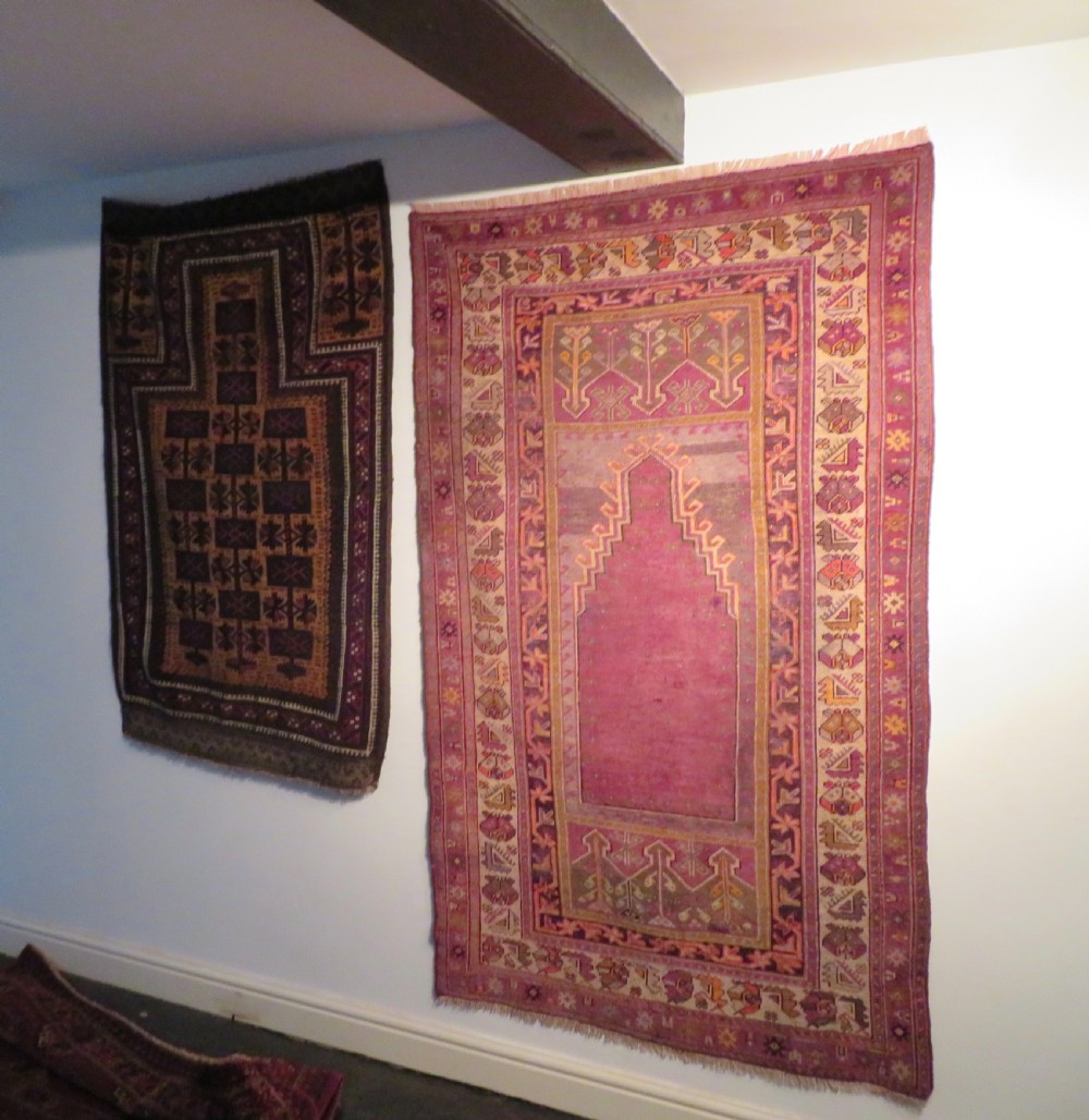 A late 19th-century hand-knotted Anatolian prayer rug featuring a deep magenta mihrab motif framed by geometric patterned borders in cream, ochre, and purple tones. View XVIII