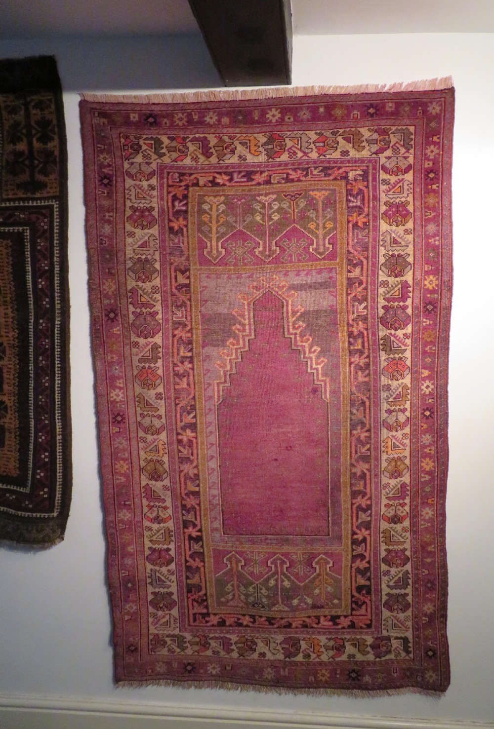 A late 19th-century hand-knotted Anatolian prayer rug featuring a deep magenta mihrab motif framed by geometric patterned borders in cream, ochre, and purple tones. View XX