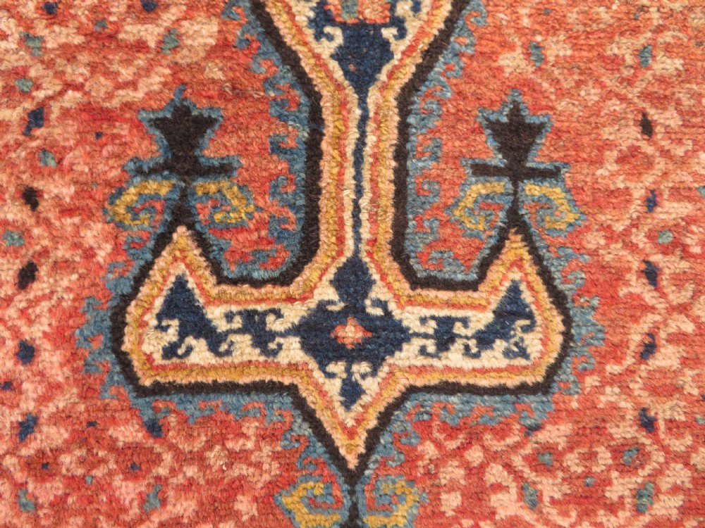 A long, narrow hand-knotted Kurdish runner rug featuring diamond medallions in navy and terracotta on a patterned rust-red field with decorative borders. View VIII