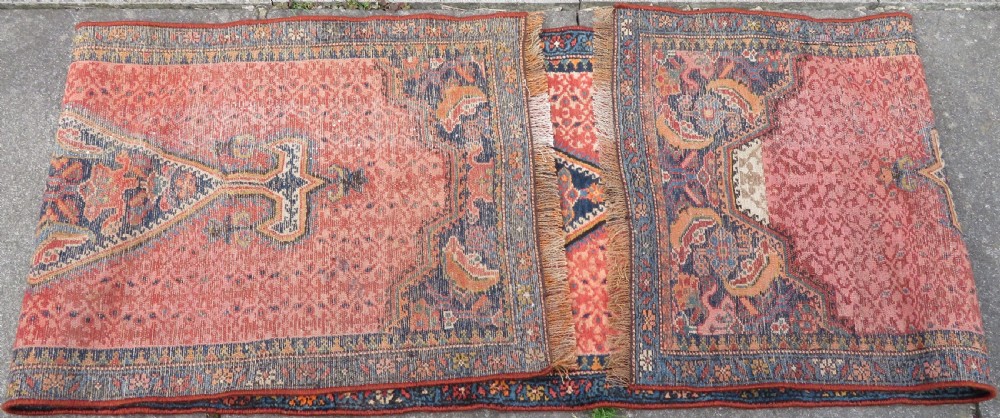 A long, narrow hand-knotted Kurdish runner rug featuring diamond medallions in navy and terracotta on a patterned rust-red field with decorative borders. View XX