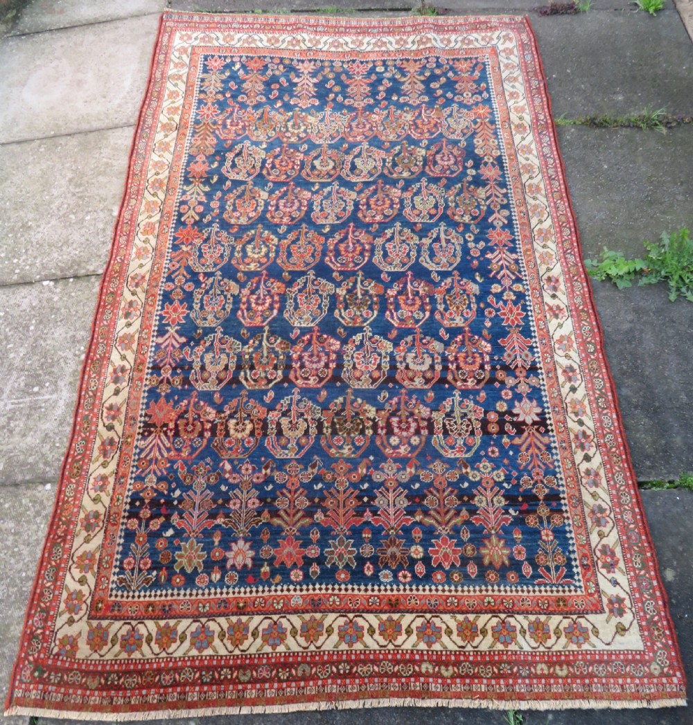 An antique Persian Qashqai Kashkuli wool rug featuring repeating boteh patterns on a deep indigo blue field surrounded by intricate cream and terracotta floral borders. View II