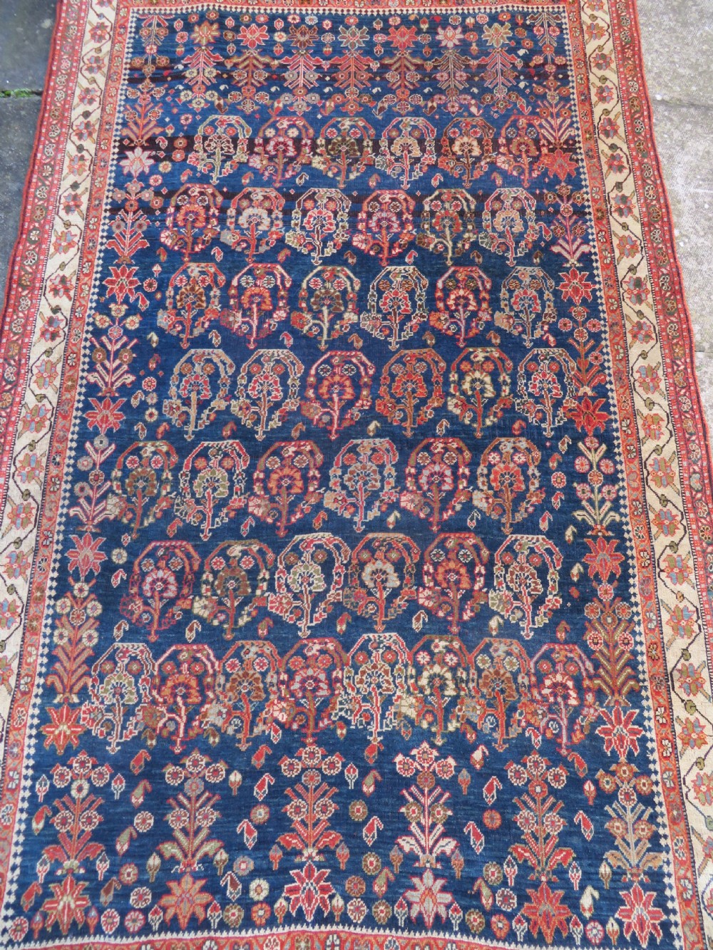An antique Persian Qashqai Kashkuli wool rug featuring repeating boteh patterns on a deep indigo blue field surrounded by intricate cream and terracotta floral borders. View III