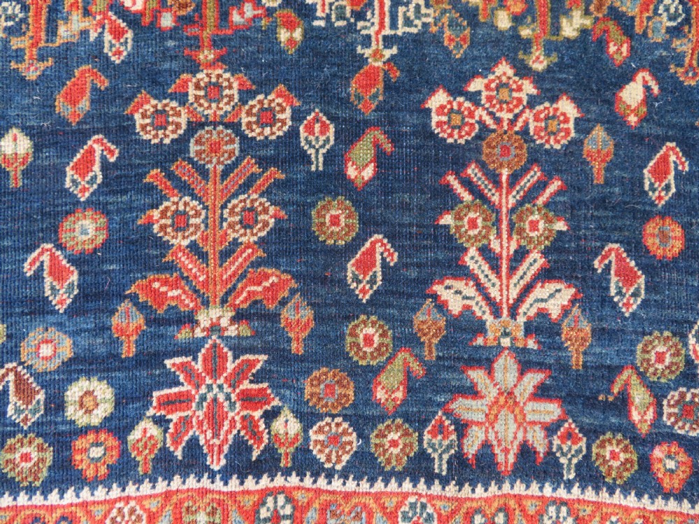 An antique Persian Qashqai Kashkuli wool rug featuring repeating boteh patterns on a deep indigo blue field surrounded by intricate cream and terracotta floral borders. View IV