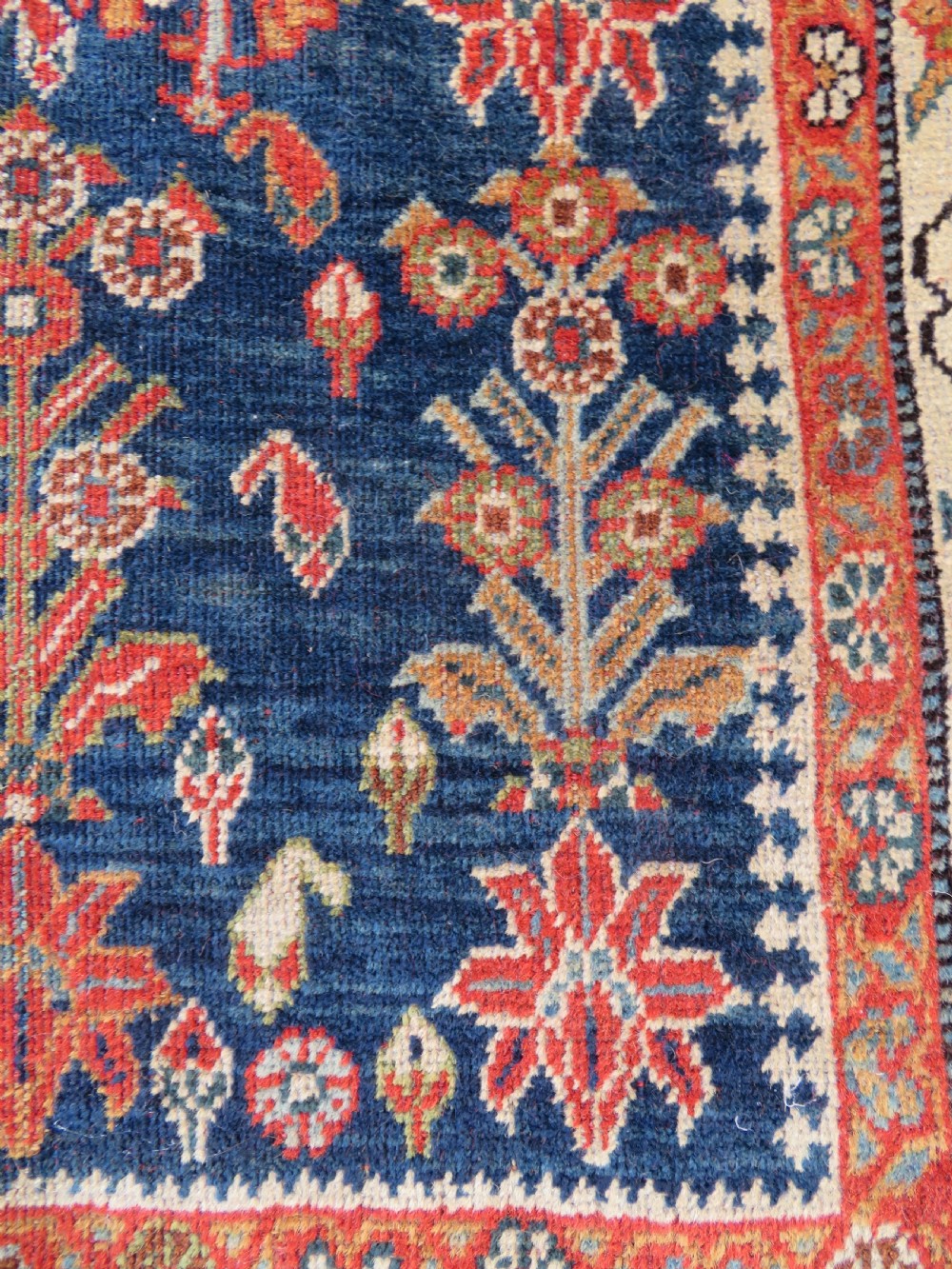An antique Persian Qashqai Kashkuli wool rug featuring repeating boteh patterns on a deep indigo blue field surrounded by intricate cream and terracotta floral borders. View V