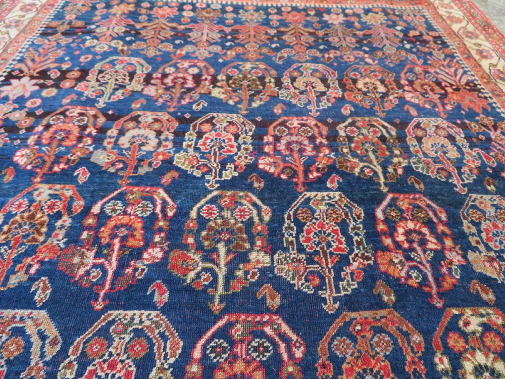 An antique Persian Qashqai Kashkuli wool rug featuring repeating boteh patterns on a deep indigo blue field surrounded by intricate cream and terracotta floral borders. View VI