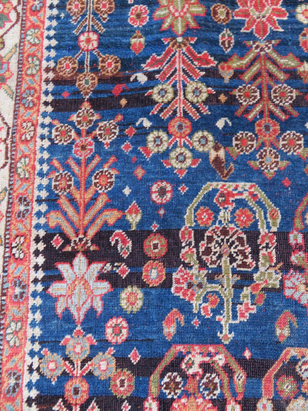 An antique Persian Qashqai Kashkuli wool rug featuring repeating boteh patterns on a deep indigo blue field surrounded by intricate cream and terracotta floral borders. View VII