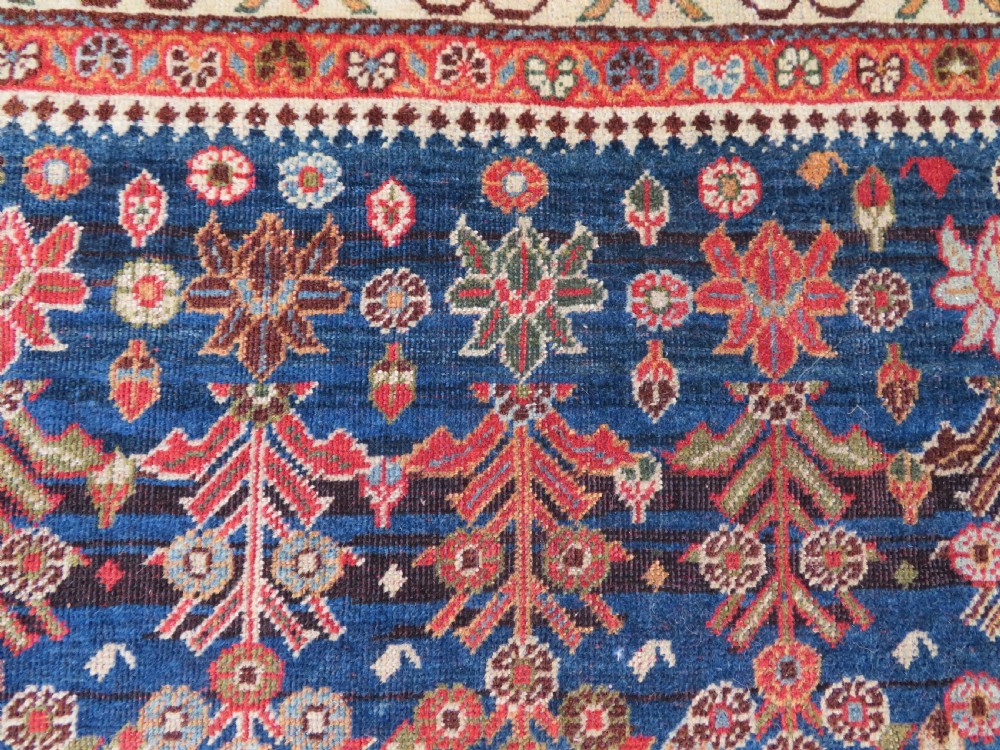 An antique Persian Qashqai Kashkuli wool rug featuring repeating boteh patterns on a deep indigo blue field surrounded by intricate cream and terracotta floral borders. View XVIII