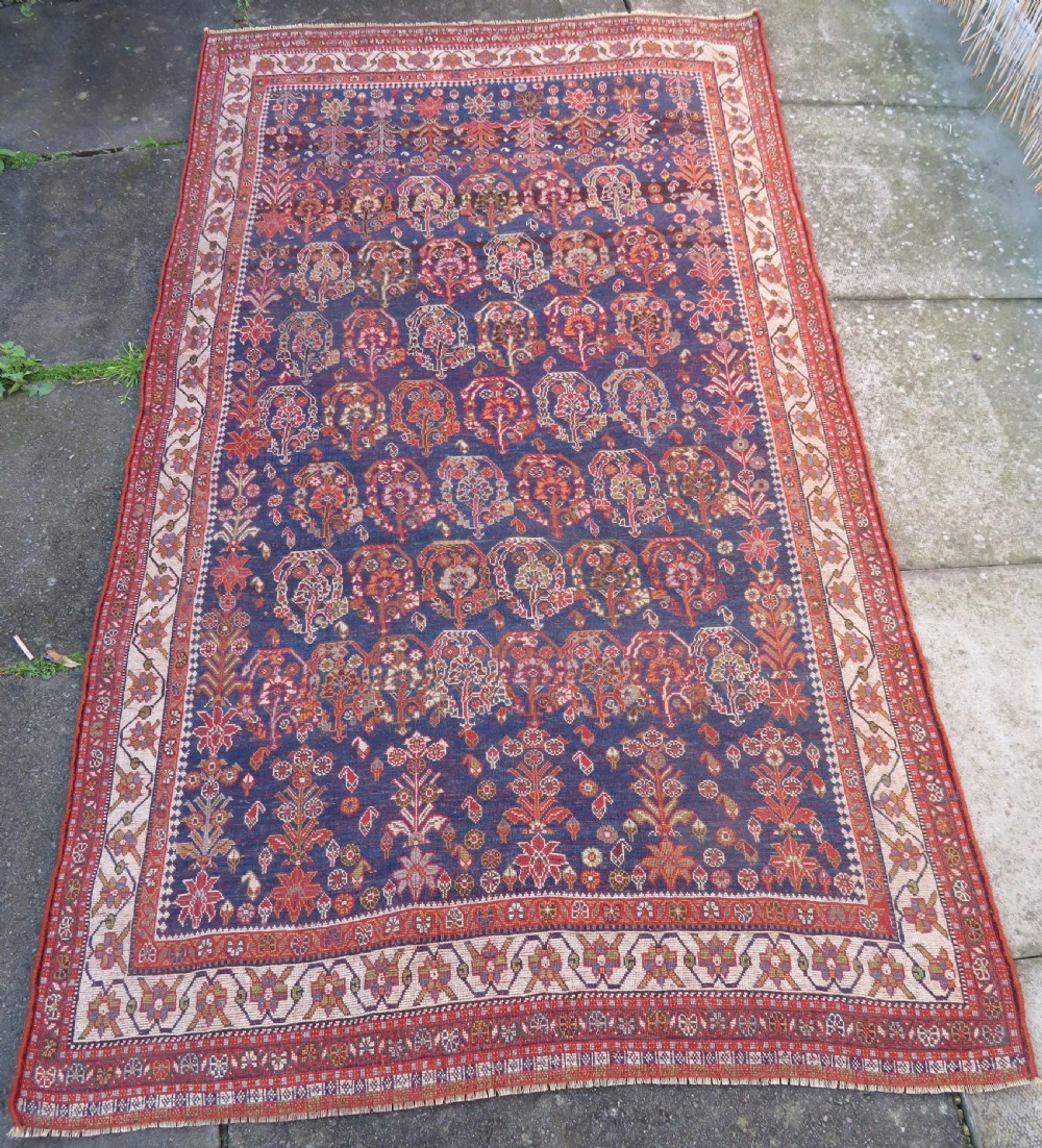 An antique Persian Qashqai Kashkuli wool rug featuring repeating boteh patterns on a deep indigo blue field surrounded by intricate cream and terracotta floral borders. View XX