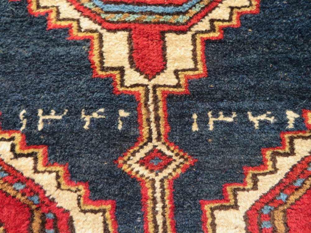 A long antique Persian Kelardasht runner rug featuring geometric diamond medallions on a dark navy blue central field framed by red and blue patterned borders. View IV
