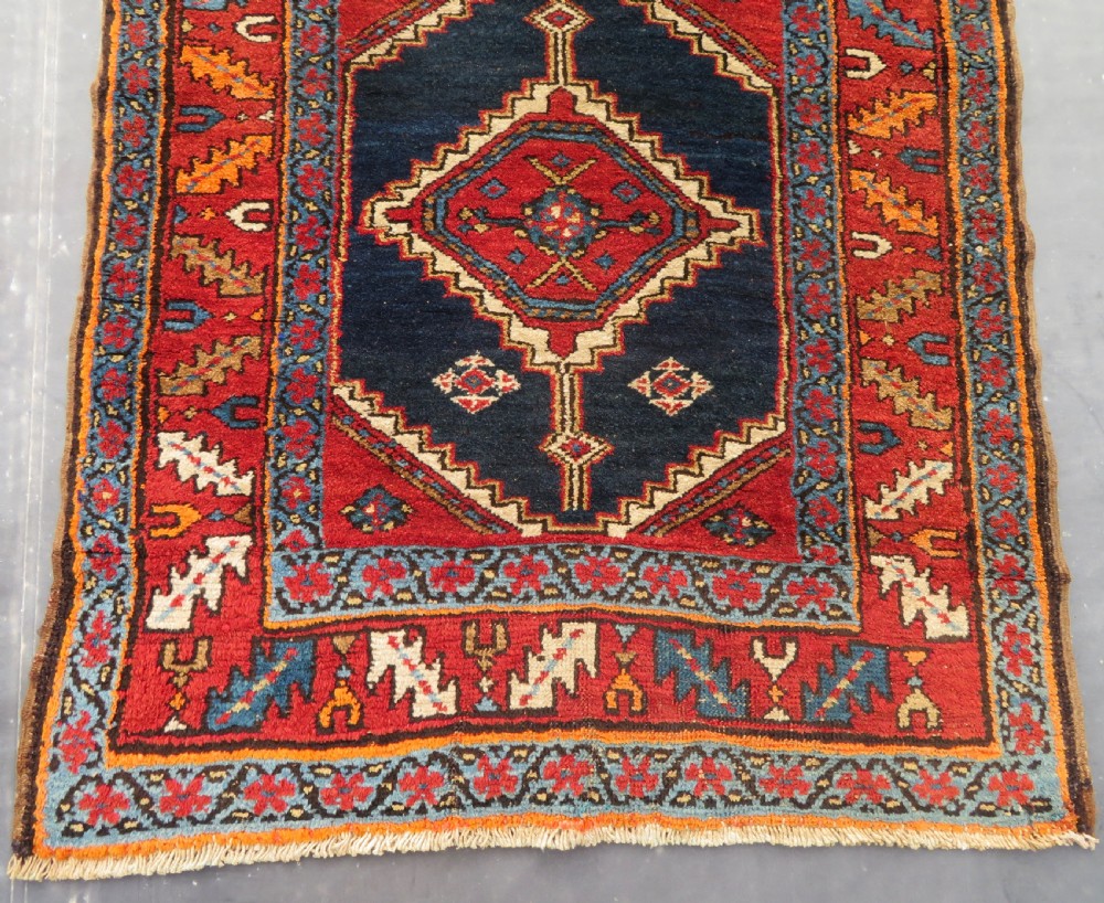 A long antique Persian Kelardasht runner rug featuring geometric diamond medallions on a dark navy blue central field framed by red and blue patterned borders. View VI