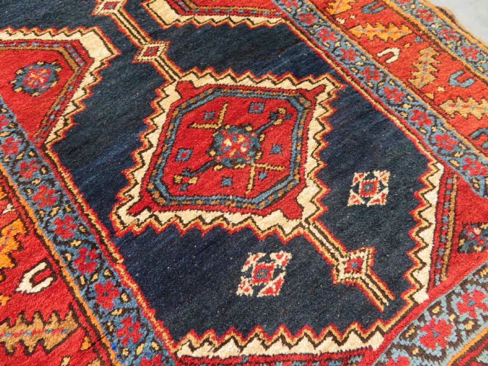 A long antique Persian Kelardasht runner rug featuring geometric diamond medallions on a dark navy blue central field framed by red and blue patterned borders. View VIII