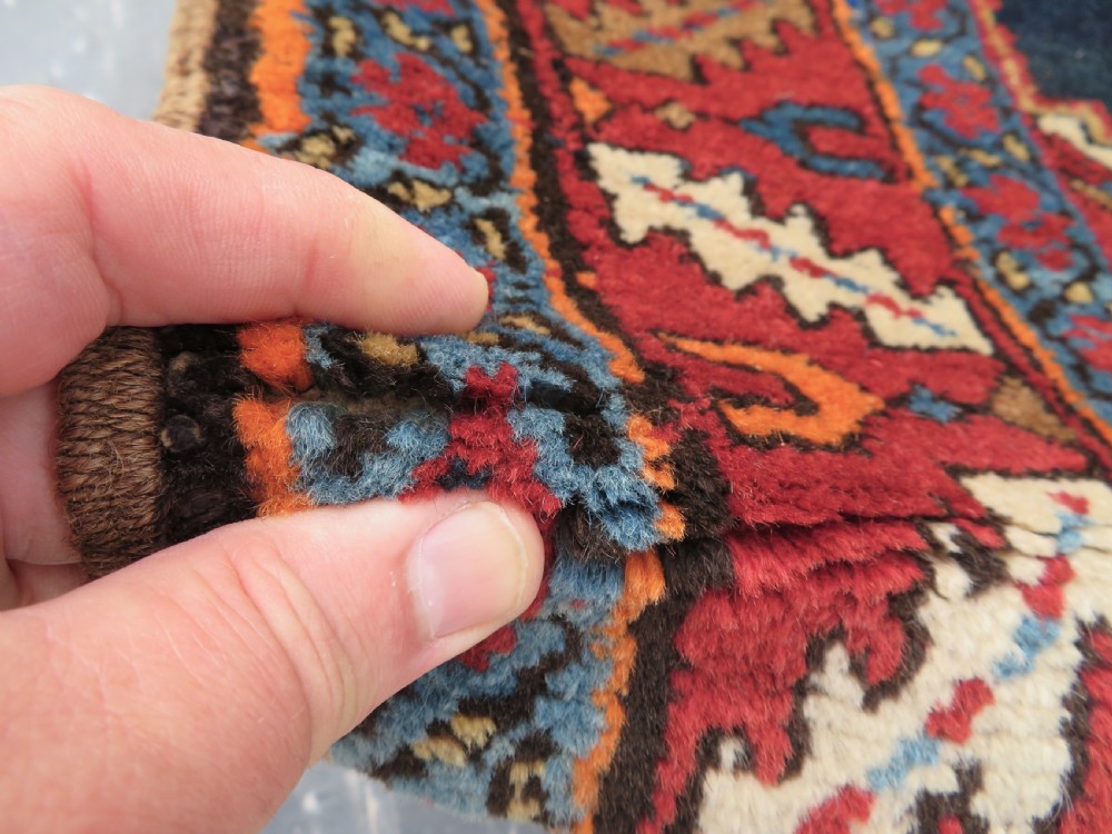 A long antique Persian Kelardasht runner rug featuring geometric diamond medallions on a dark navy blue central field framed by red and blue patterned borders. View X