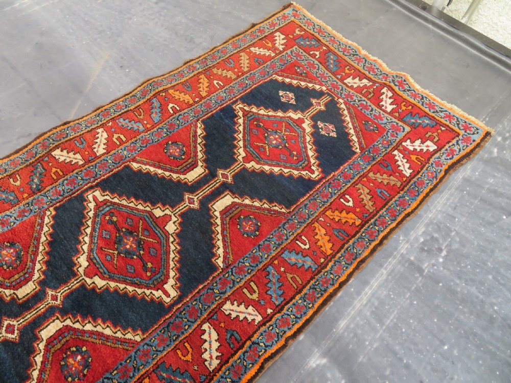 A long antique Persian Kelardasht runner rug featuring geometric diamond medallions on a dark navy blue central field framed by red and blue patterned borders. View XIII