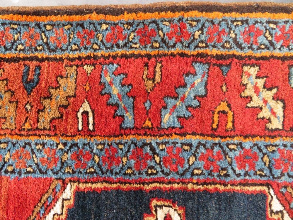 A long antique Persian Kelardasht runner rug featuring geometric diamond medallions on a dark navy blue central field framed by red and blue patterned borders. View XVI