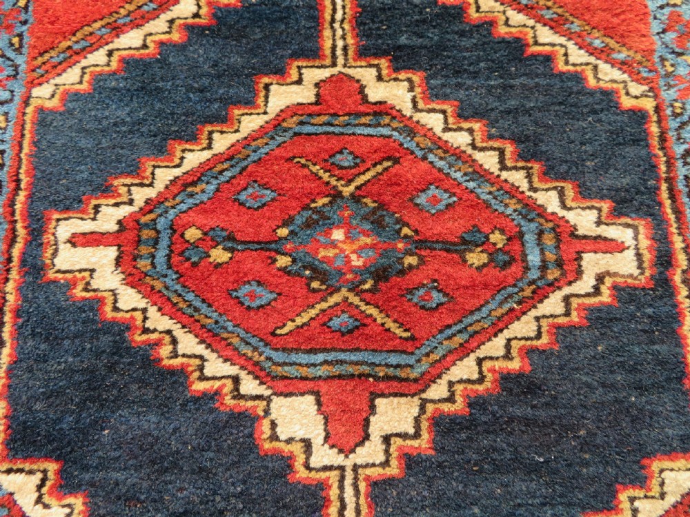 A long antique Persian Kelardasht runner rug featuring geometric diamond medallions on a dark navy blue central field framed by red and blue patterned borders. View XXI