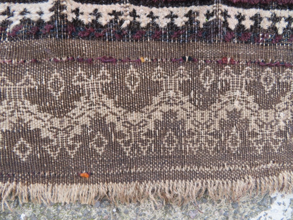 An antique Baluch wool prayer rug featuring a stepped arched mihrab design on a camel-coloured field with deep red and navy geometric motifs. View XV