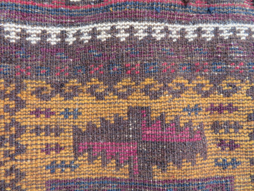 An antique Baluch wool prayer rug featuring a stepped arched mihrab design on a camel-coloured field with deep red and navy geometric motifs. View XVIII