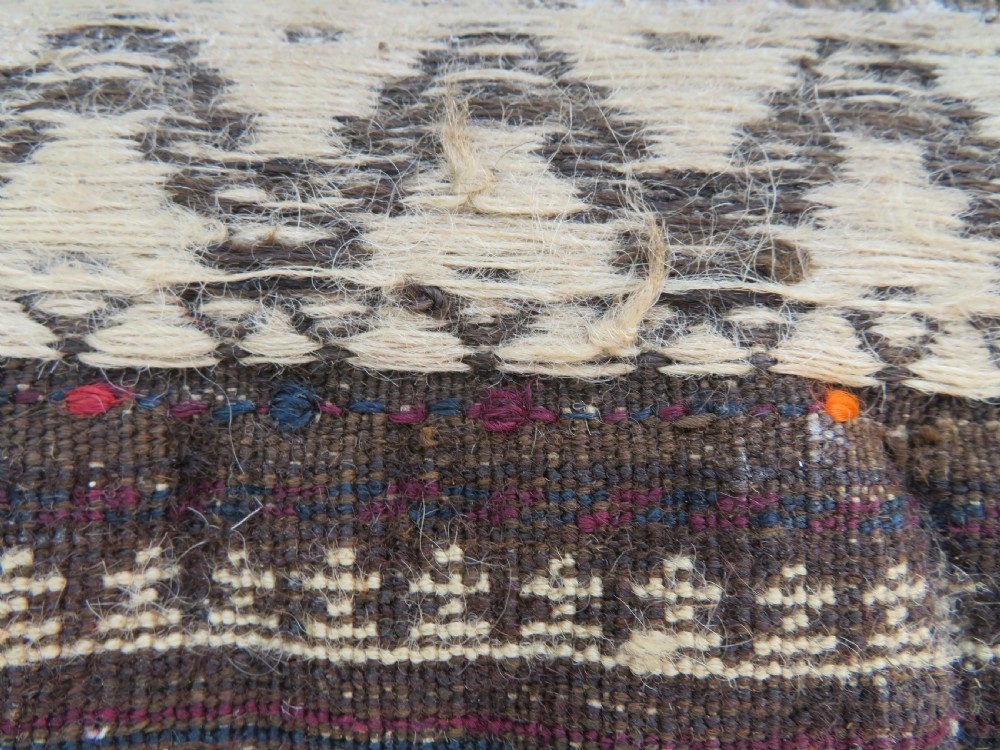 An antique Baluch wool prayer rug featuring a stepped arched mihrab design on a camel-coloured field with deep red and navy geometric motifs. View XIX