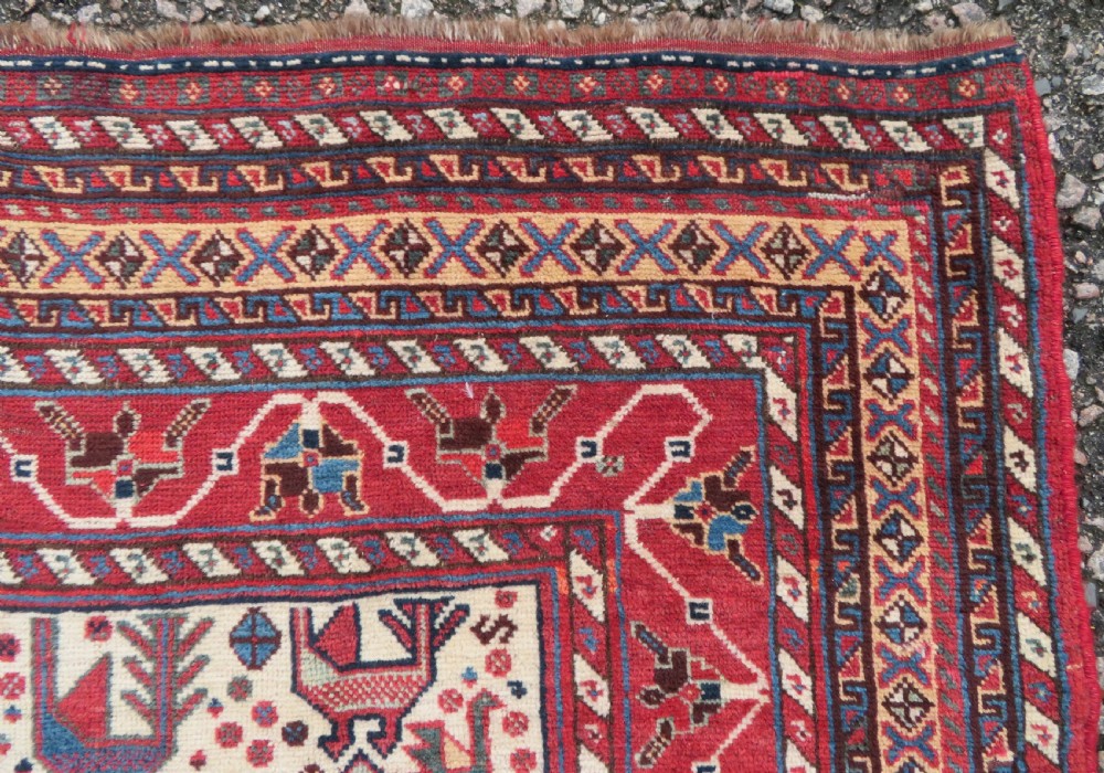 A late 19th-century Persian Qashqai hand-knotted wool rug featuring a navy blue field filled with stylized red peacock motifs, a central cream diamond medallion, and a wide red geometric border. View VII