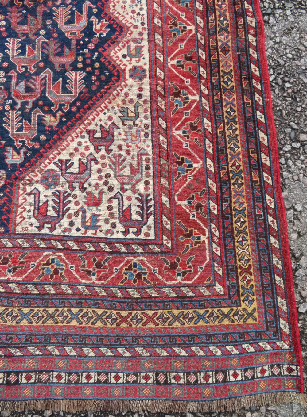 A late 19th-century Persian Qashqai hand-knotted wool rug featuring a navy blue field filled with stylized red peacock motifs, a central cream diamond medallion, and a wide red geometric border. View VIII