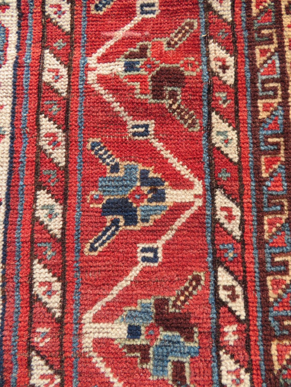 A late 19th-century Persian Qashqai hand-knotted wool rug featuring a navy blue field filled with stylized red peacock motifs, a central cream diamond medallion, and a wide red geometric border. View XIX