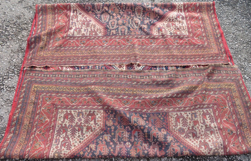 A late 19th-century Persian Qashqai hand-knotted wool rug featuring a navy blue field filled with stylized red peacock motifs, a central cream diamond medallion, and a wide red geometric border. View XXVI