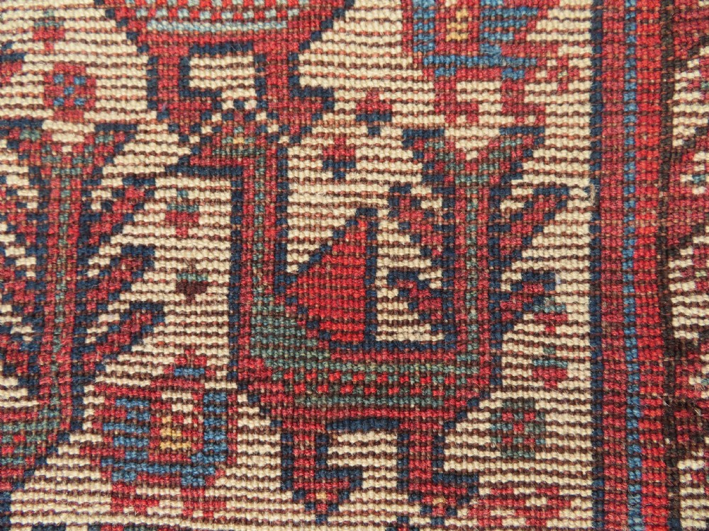 A late 19th-century Persian Qashqai hand-knotted wool rug featuring a navy blue field filled with stylized red peacock motifs, a central cream diamond medallion, and a wide red geometric border. View XXVIII