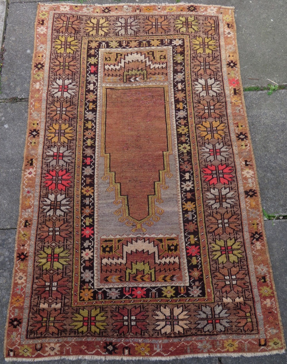 A late 19th-century hand-knotted Turkish Milas wool prayer rug featuring a central stepped mihrab niche surrounded by a wide geometric star pattern border in terracotta, gold, and earthy brown tones. View II