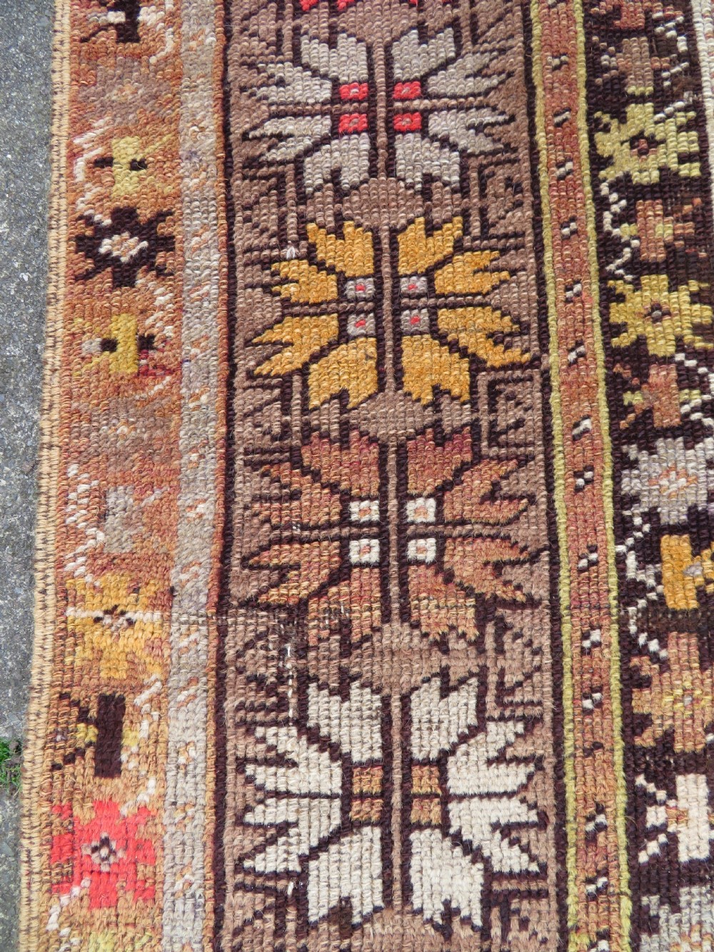 A late 19th-century hand-knotted Turkish Milas wool prayer rug featuring a central stepped mihrab niche surrounded by a wide geometric star pattern border in terracotta, gold, and earthy brown tones. View VIII