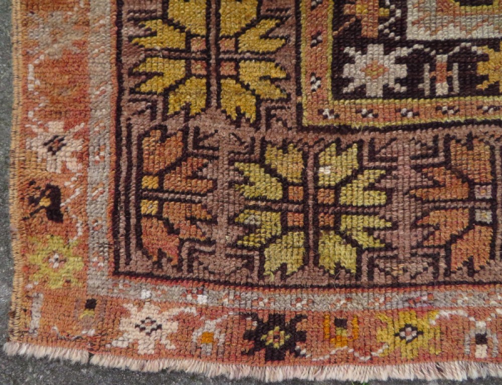 A late 19th-century hand-knotted Turkish Milas wool prayer rug featuring a central stepped mihrab niche surrounded by a wide geometric star pattern border in terracotta, gold, and earthy brown tones. View IX