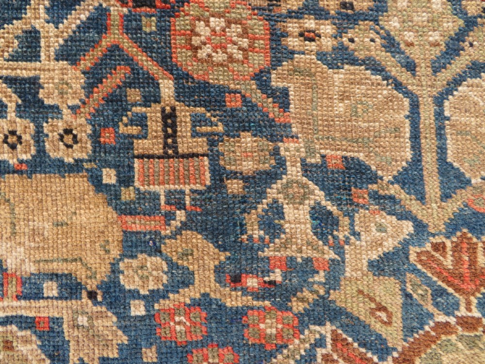 An antique Persian Qashqai Millefleurs wool rug featuring a central arch field filled with dense floral motifs in navy blue, terracotta, and ochre tones. View VII