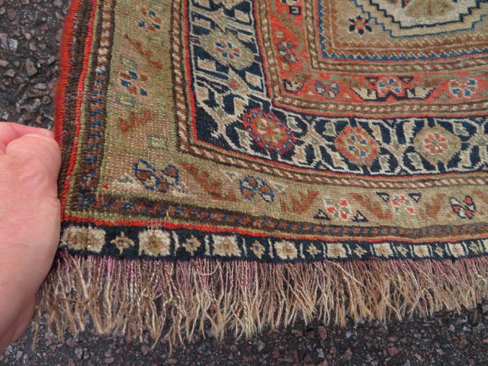 An antique Persian Qashqai Millefleurs wool rug featuring a central arch field filled with dense floral motifs in navy blue, terracotta, and ochre tones. View IX