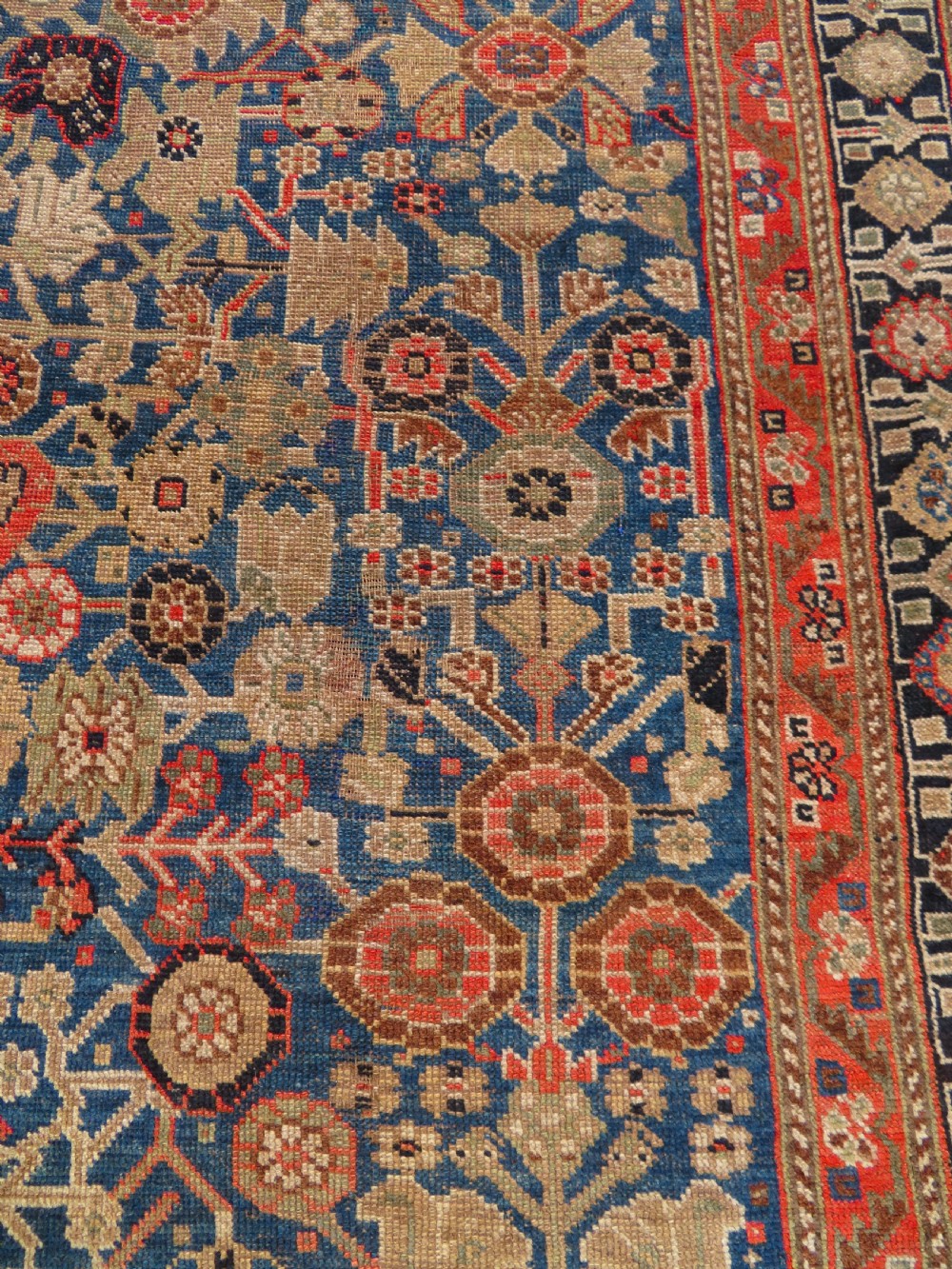 An antique Persian Qashqai Millefleurs wool rug featuring a central arch field filled with dense floral motifs in navy blue, terracotta, and ochre tones. View XVI