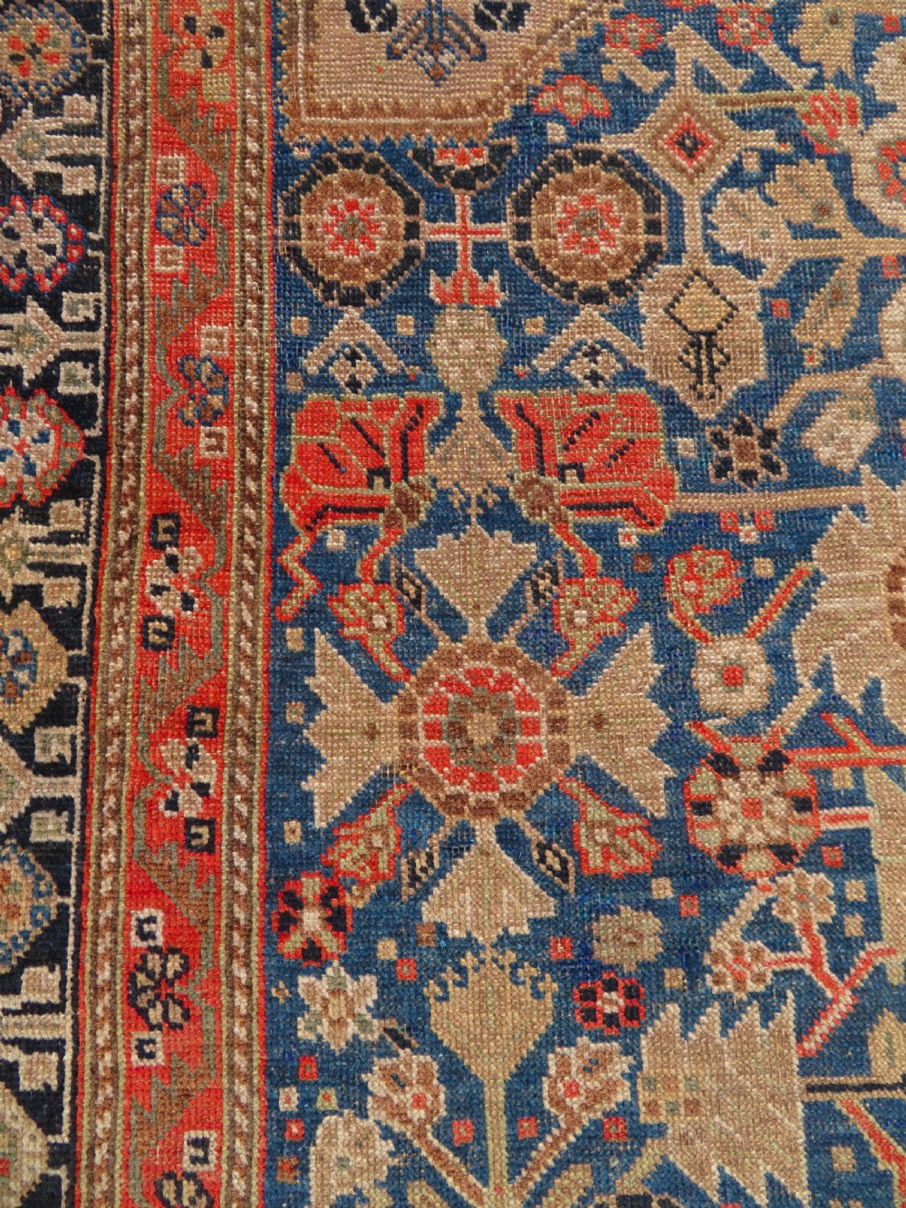 An antique Persian Qashqai Millefleurs wool rug featuring a central arch field filled with dense floral motifs in navy blue, terracotta, and ochre tones. View XVIII