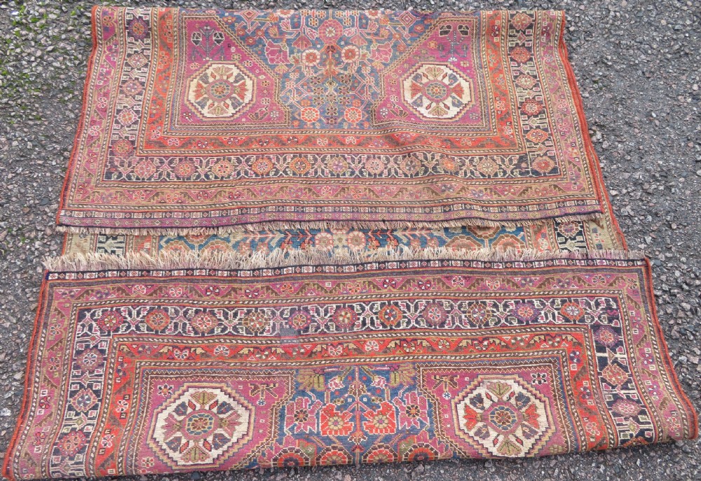 An antique Persian Qashqai Millefleurs wool rug featuring a central arch field filled with dense floral motifs in navy blue, terracotta, and ochre tones. View XX