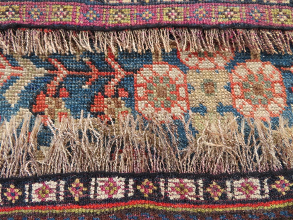 An antique Persian Qashqai Millefleurs wool rug featuring a central arch field filled with dense floral motifs in navy blue, terracotta, and ochre tones. View XXIII