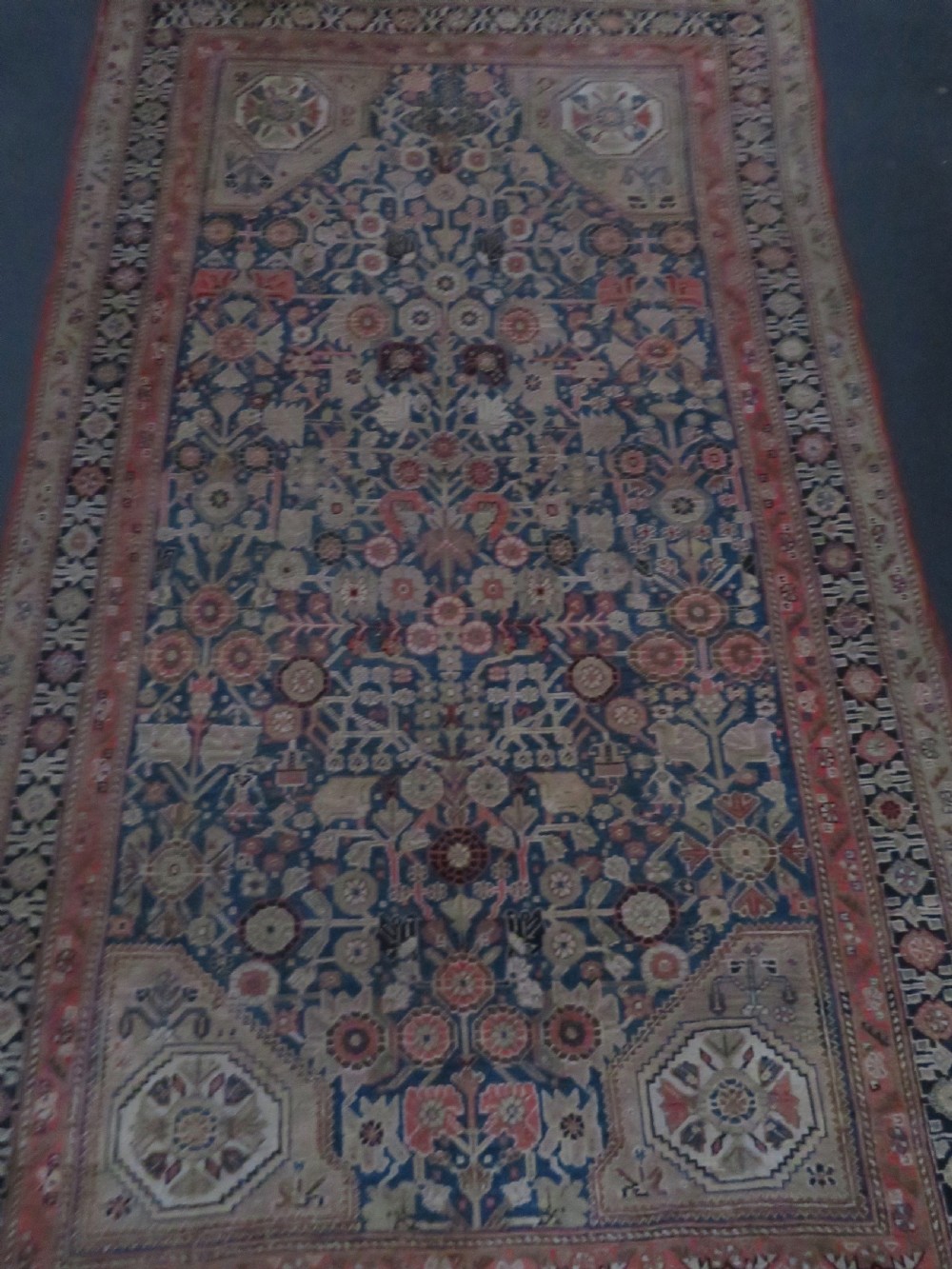 An antique Persian Qashqai Millefleurs wool rug featuring a central arch field filled with dense floral motifs in navy blue, terracotta, and ochre tones. View XXVI