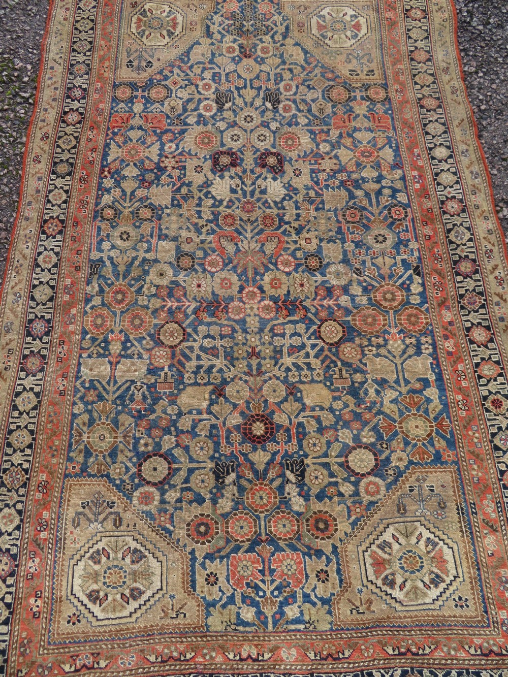 An antique Persian Qashqai Millefleurs wool rug featuring a central arch field filled with dense floral motifs in navy blue, terracotta, and ochre tones. View XXVII